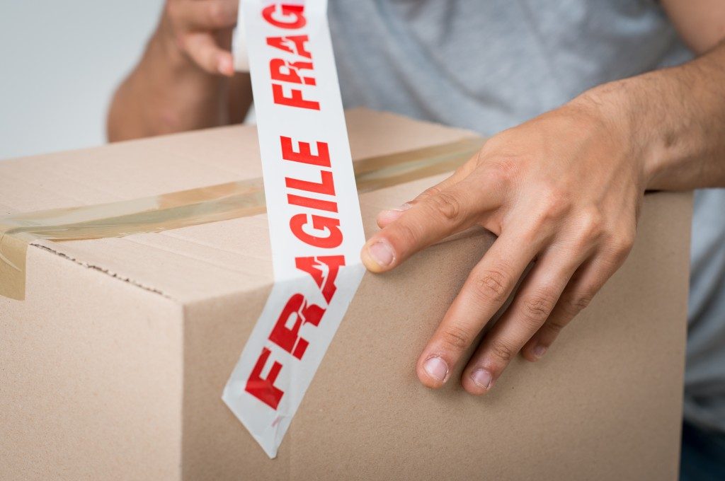 man placing a fragile sign on a box