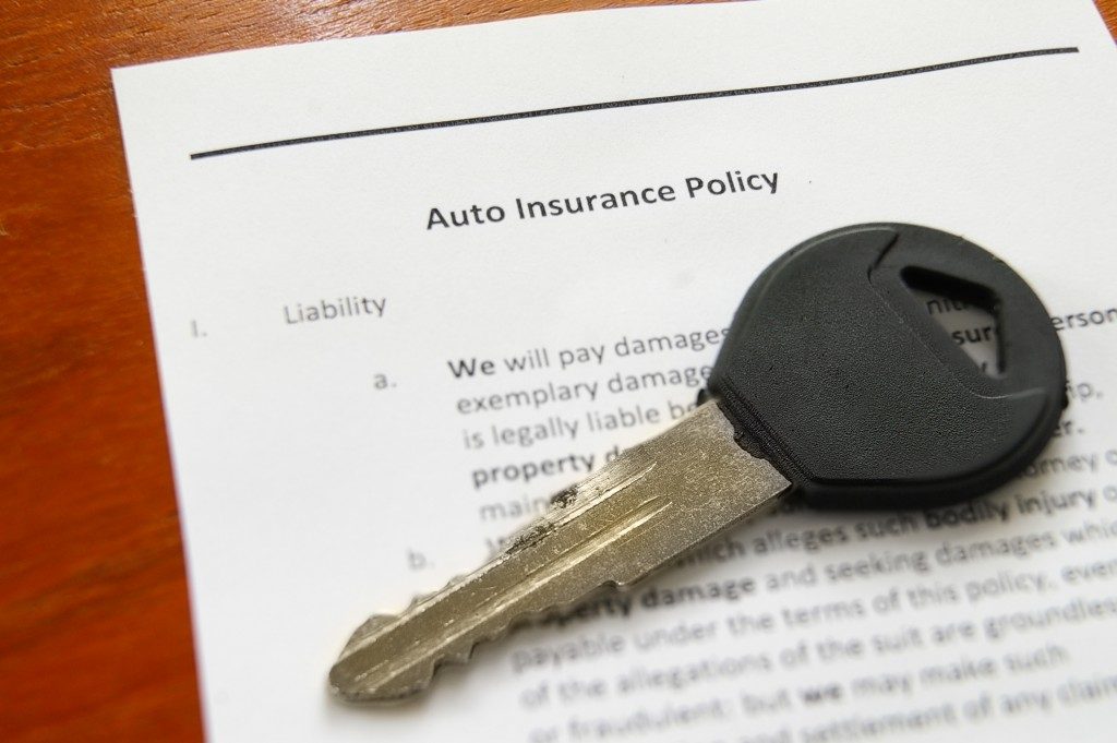 closeup of car key with an auto insurance policy