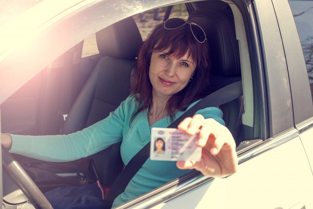 woman in the car showing her license